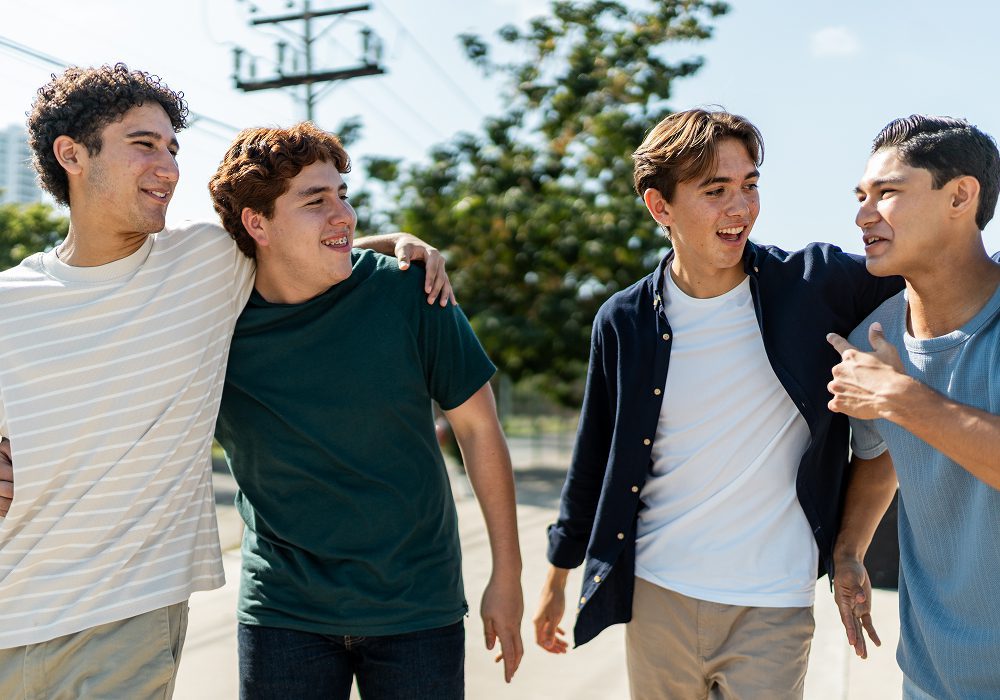 Four smiling teenage friends walking outdoors together