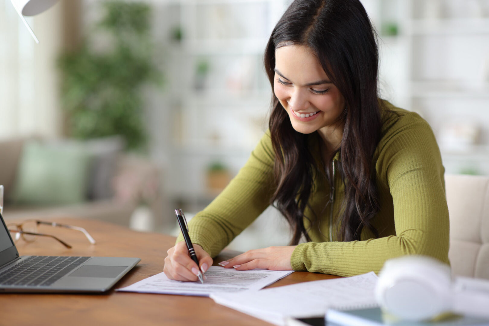 Smiling woman studying at home desk with laptop