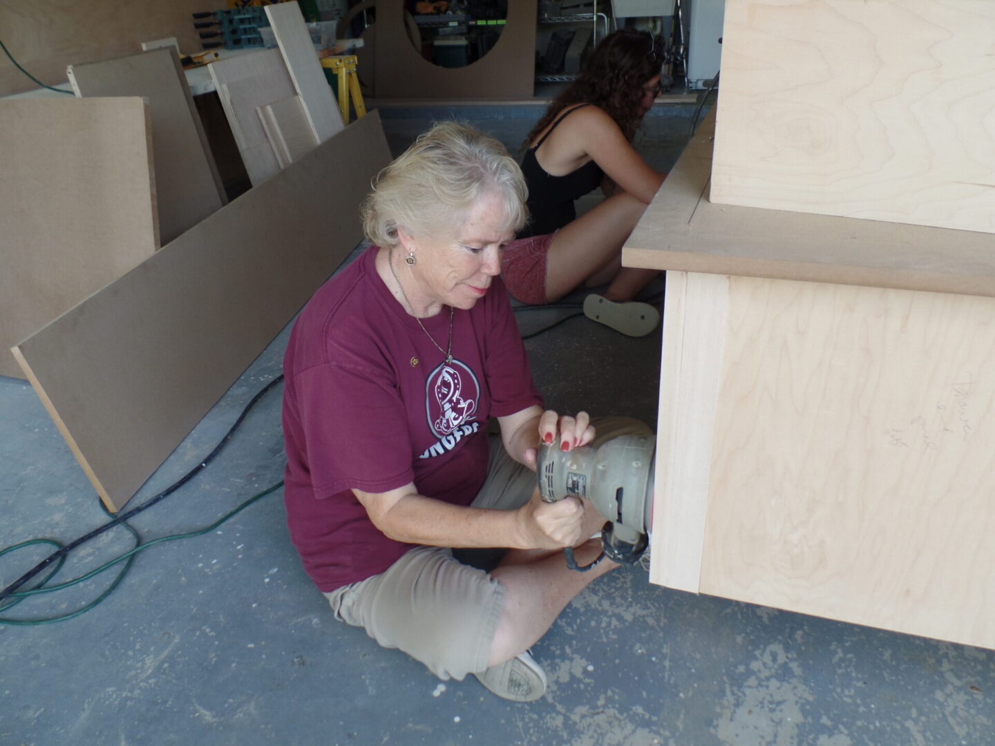 Woman using sander on wooden cabinet